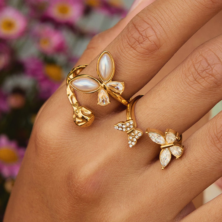 A gold butterfly ring with pearls on a hand