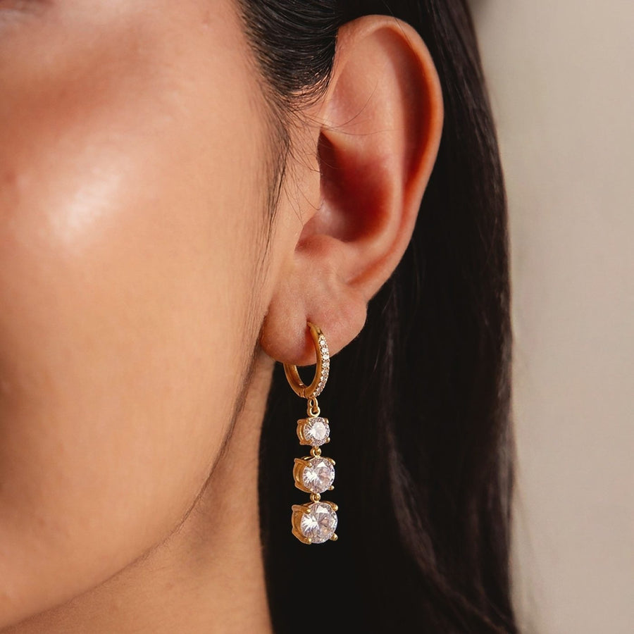 A long gold earring with clear stones