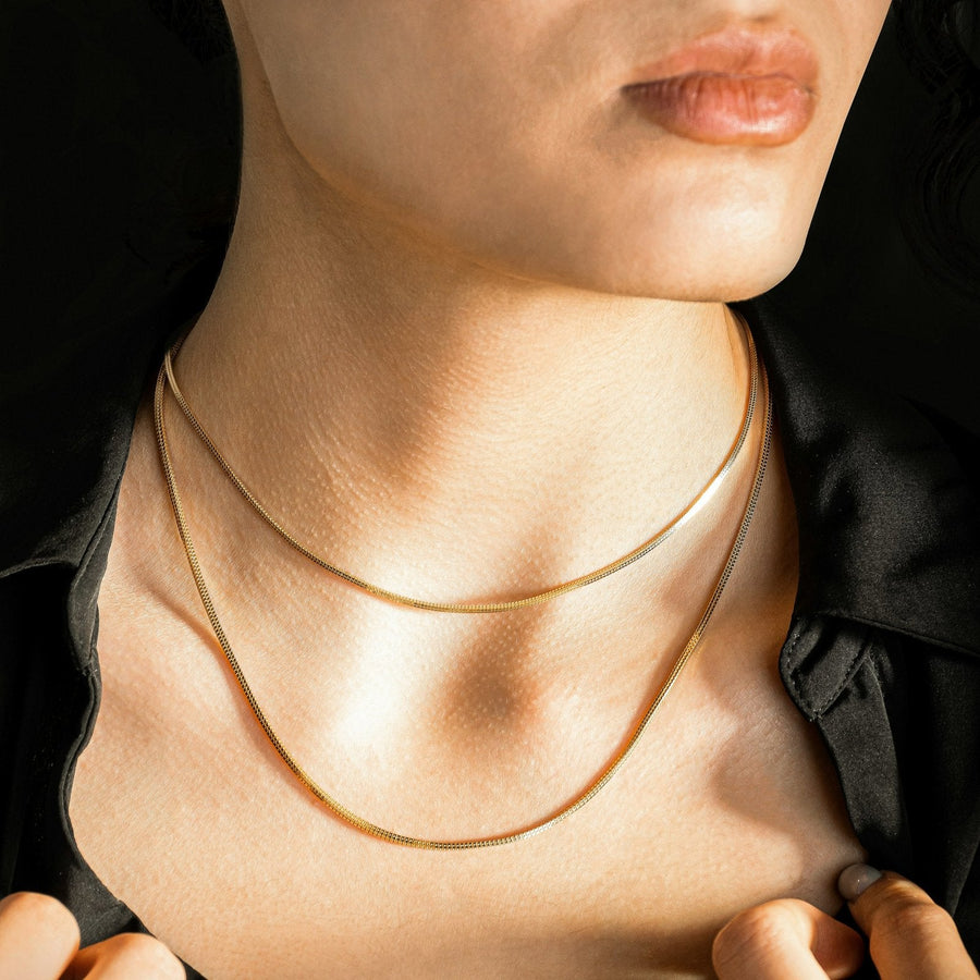 Two gold snake chains worn at the collarbone