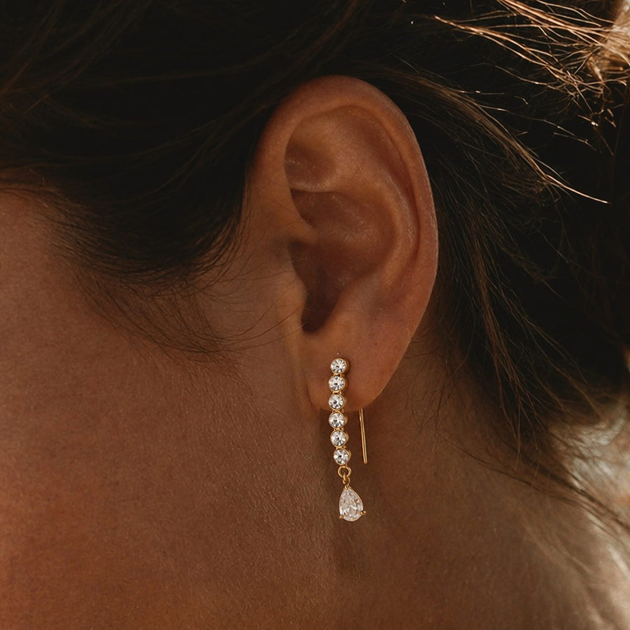 A gold drop earring with a row of small stones