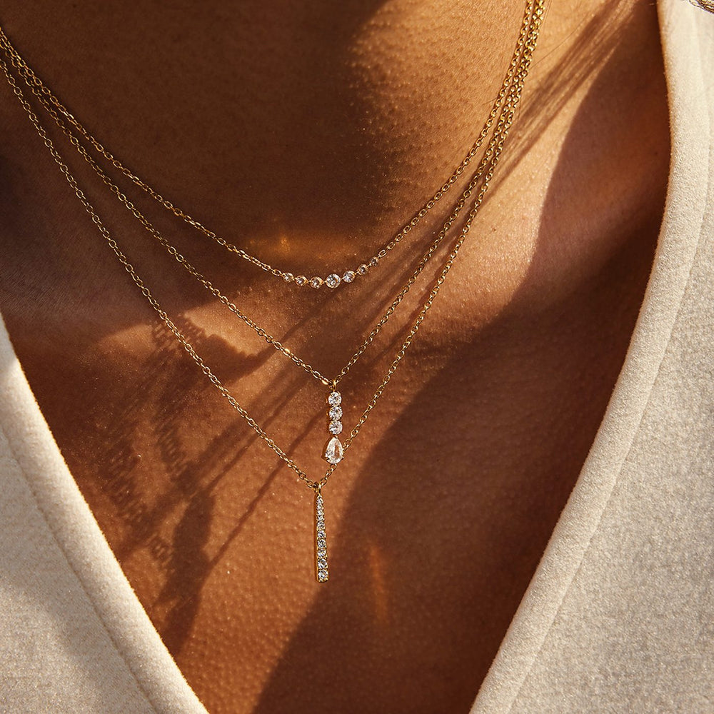 Layered fine gold chains in warm sunlight