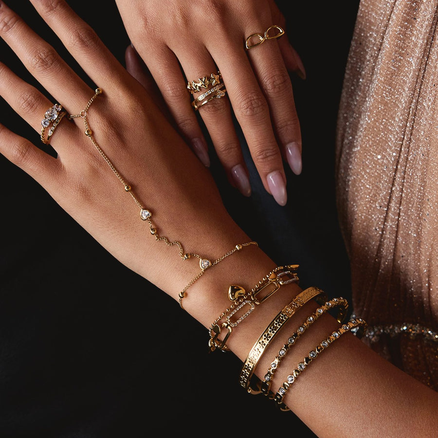Hands wearing gold bracelets and a hand chain
