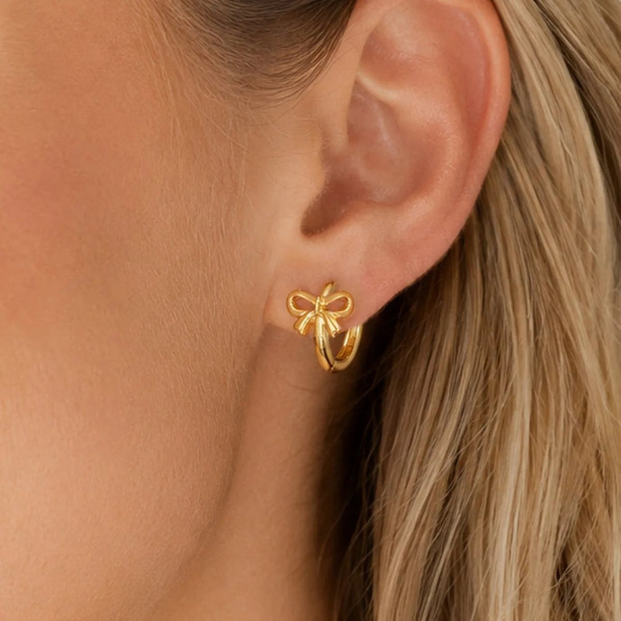 Noeud Bow Gold Huggie Earrings on the ear, worn