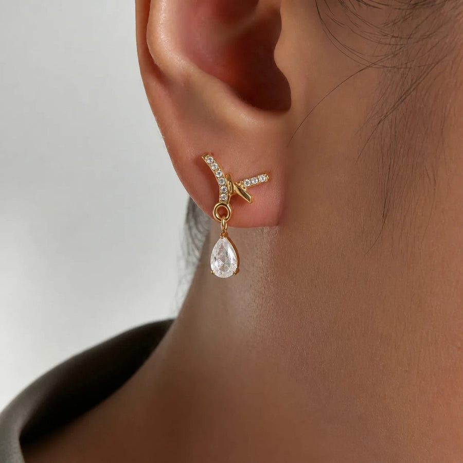 Noor Crossover Gold Teardrop Earrings on the ear, worn